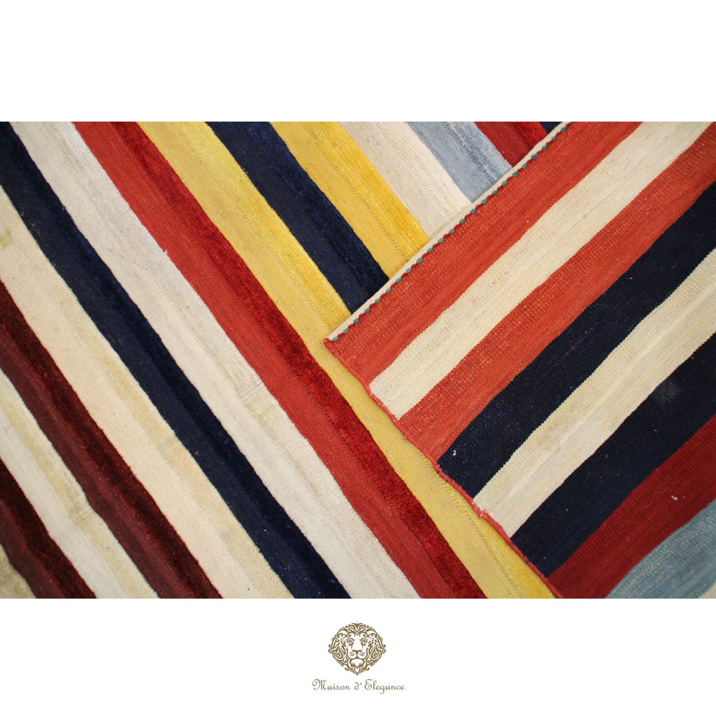Colorful striped pattern with geometric design on a textured surface, featuring red, yellow, blue, and beige colors.