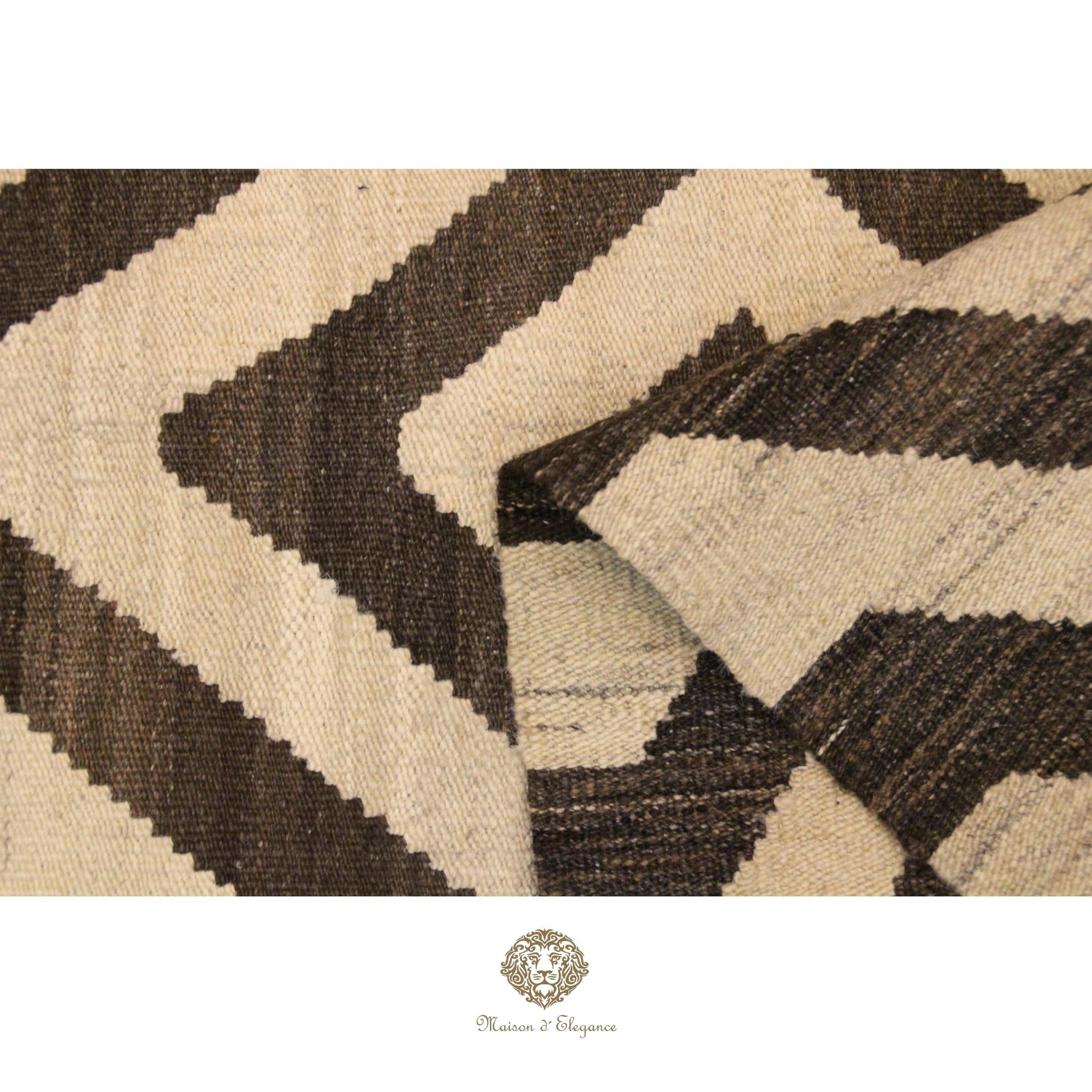 Close-up of a textured fabric with black and beige pattern, featuring a brand logo at the bottom.