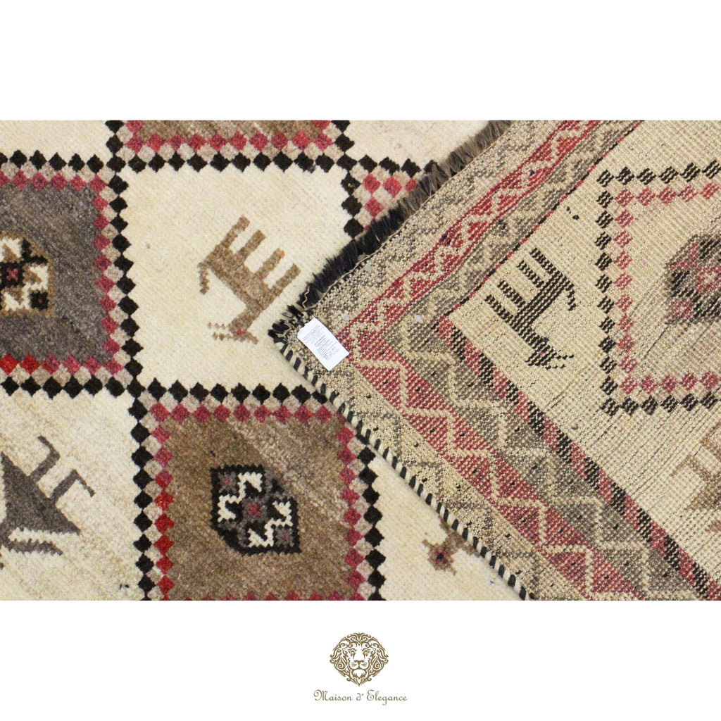 Close-up of a patterned rug with geometric designs on a white background, featuring a brand logo.