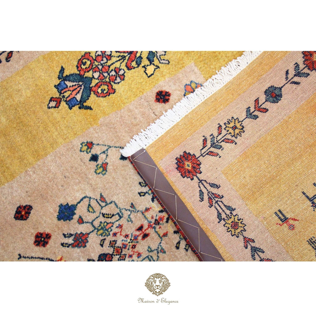 Close-up of a patterned rug with floral designs and a brand logo at the bottom.