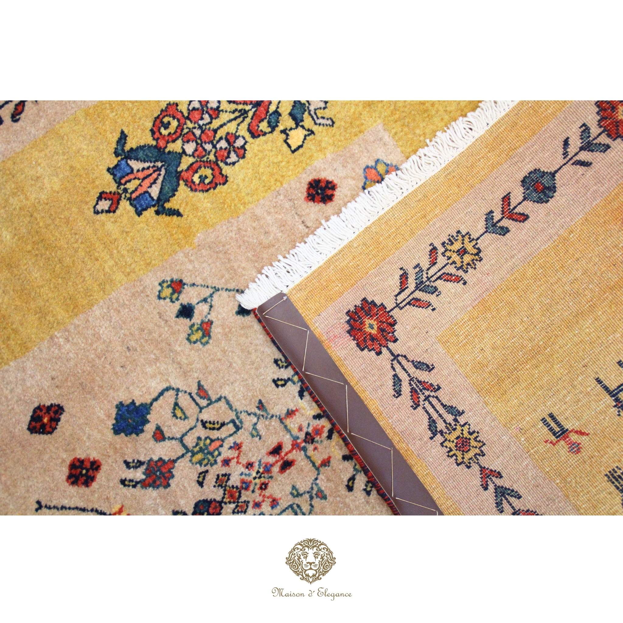 Close-up of a patterned rug with floral designs and a brand logo at the bottom.