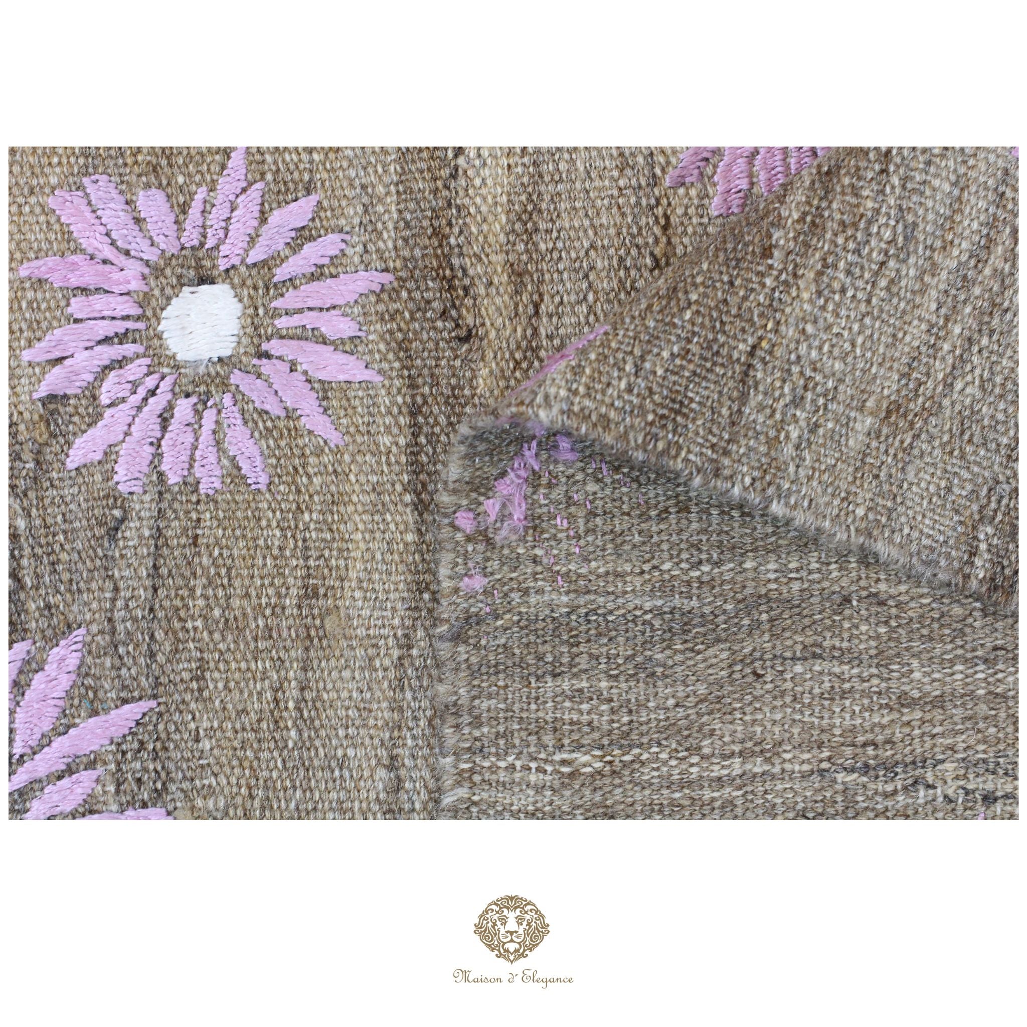 Textile with embroidered pink flowers on a beige background