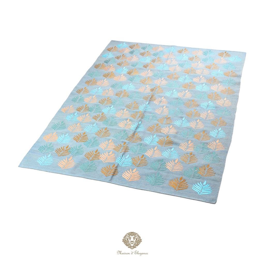 Light blue fabric with gold and green leaf pattern on a blue background