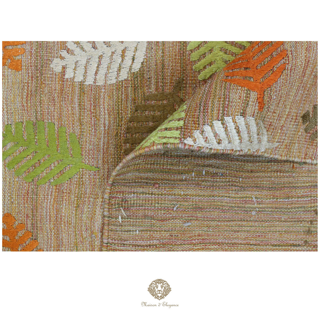 Textile with leaf pattern featuring orange, green, and brown colors on a white background.