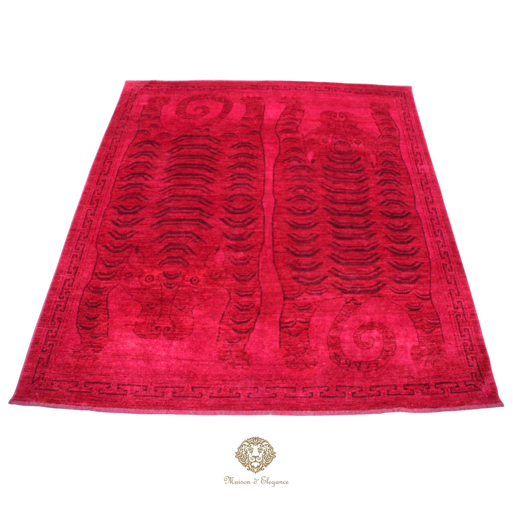 Red patterned rug with a brand logo at the bottom center on a red background