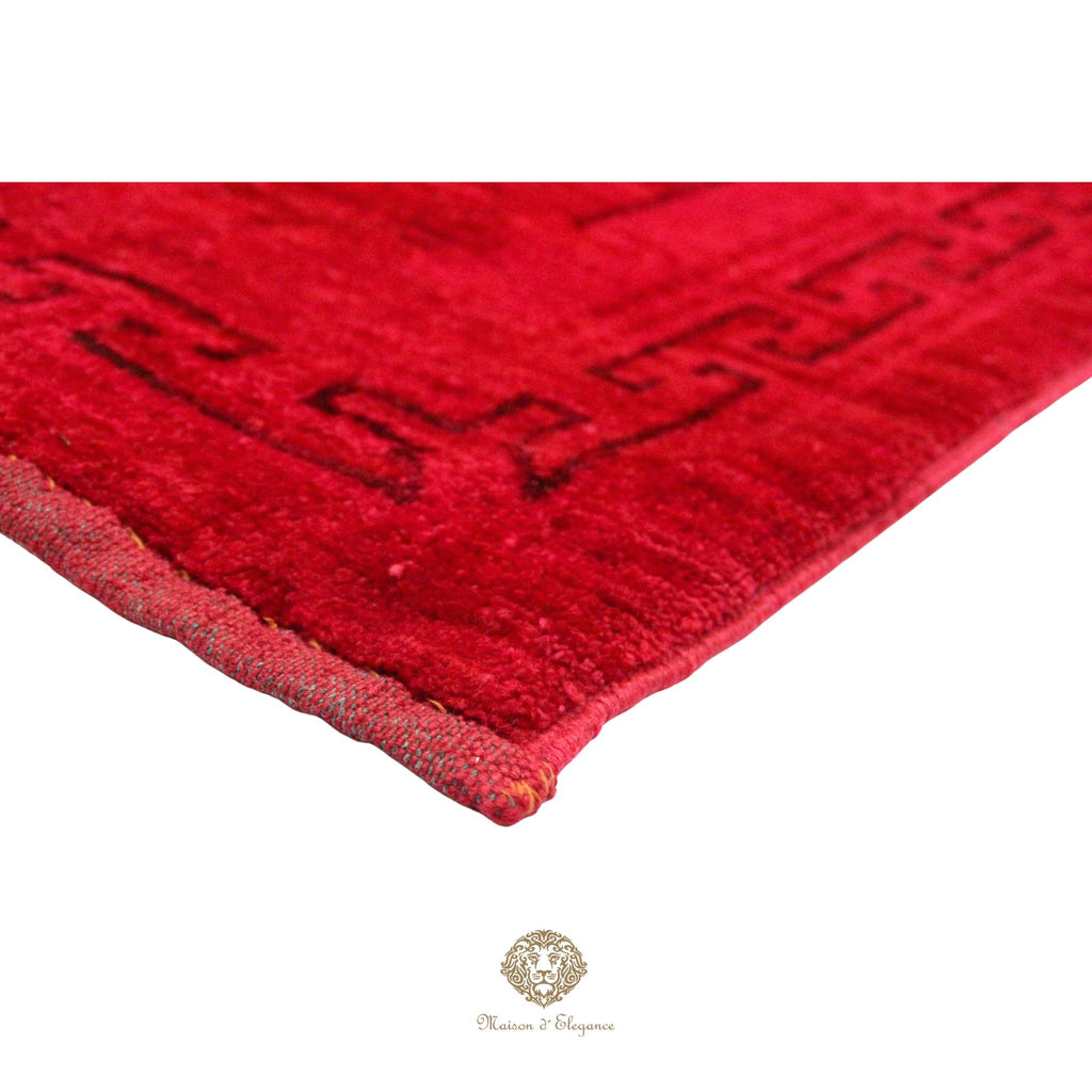Close-up of a red textured rug with a brand logo in the corner.