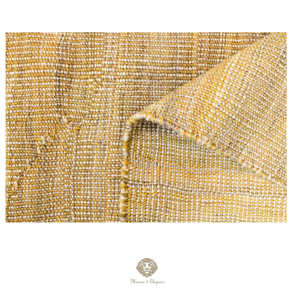 Close-up of textured gold fabric with a brand logo at the bottom.