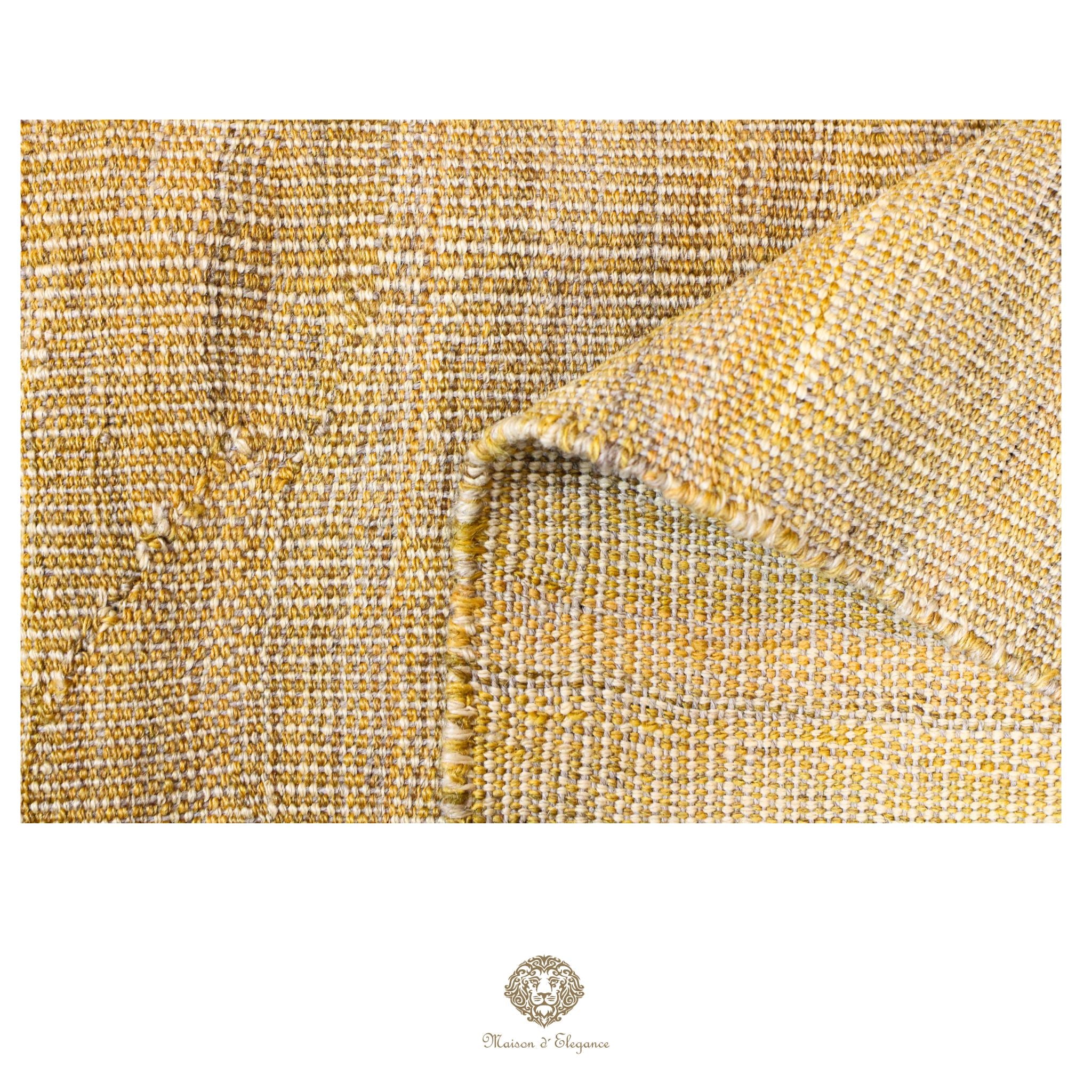 Close-up of textured gold fabric with a brand logo at the bottom.
