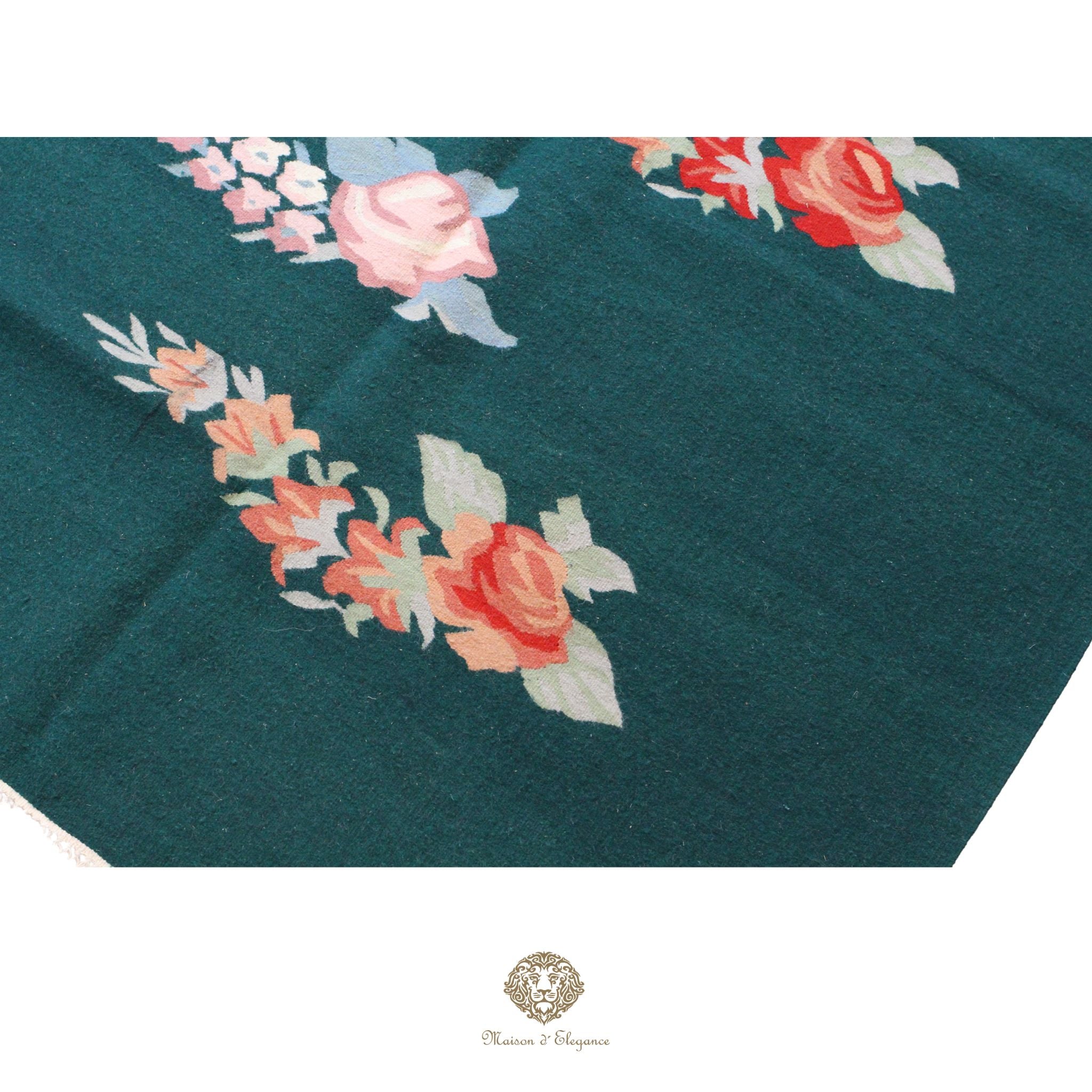 Floral embroidery on a teal fabric with a brand logo at the bottom.