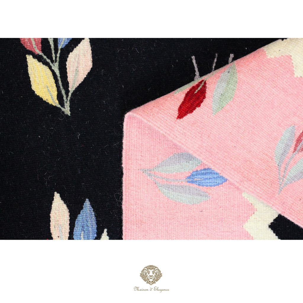 Close-up of a floral-patterned fabric with black, pink, and multicolor leaves on a black background.