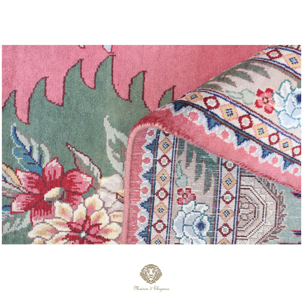 Close-up of a floral-patterned rug with a brand logo in the corner.