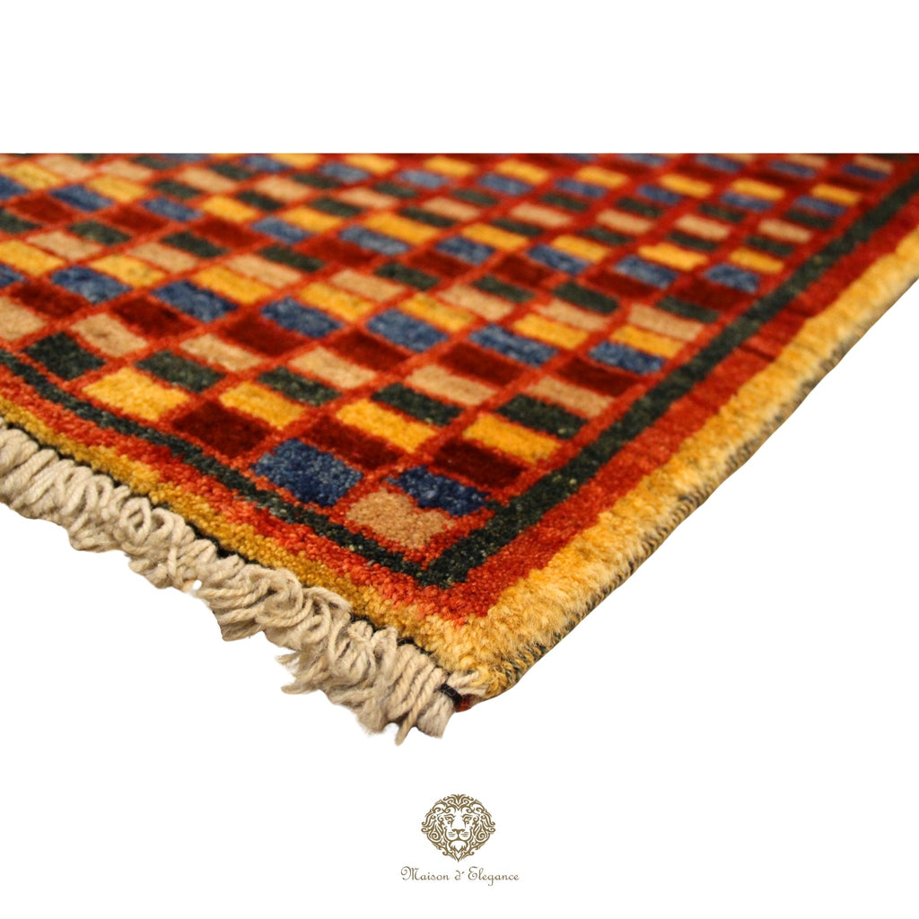 Close-up of a checkered patterned rug with fringed edge on a red background