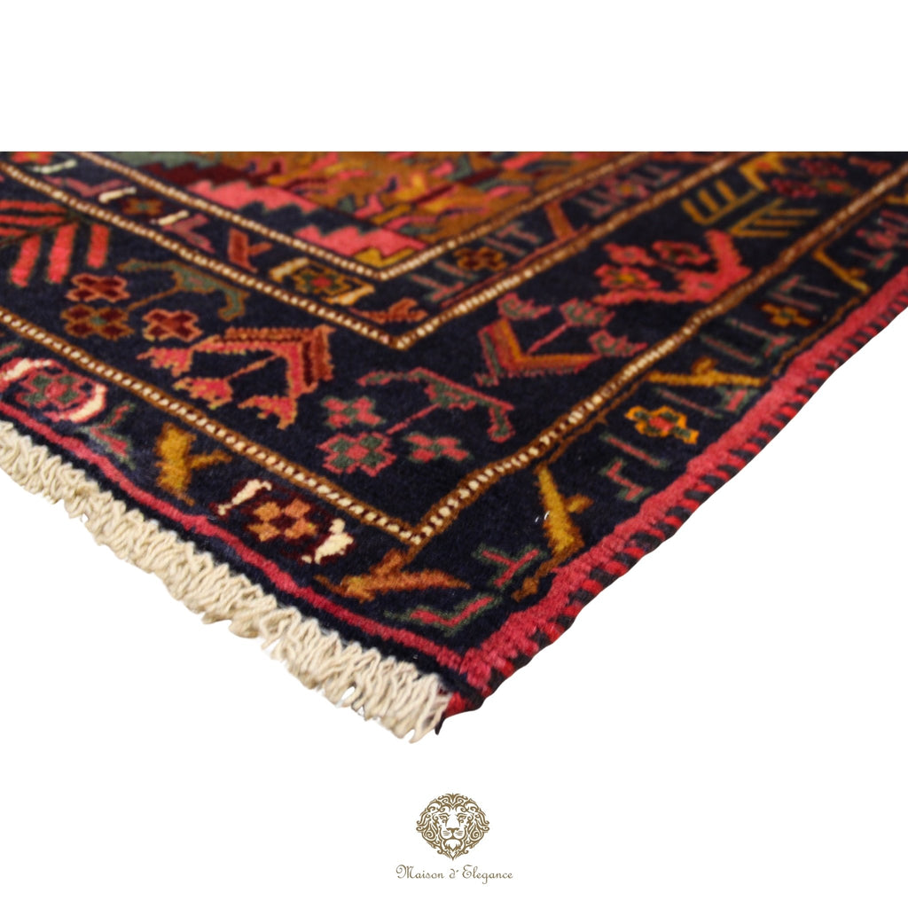 Close-up of a patterned rug with visible brand logo at the bottom.