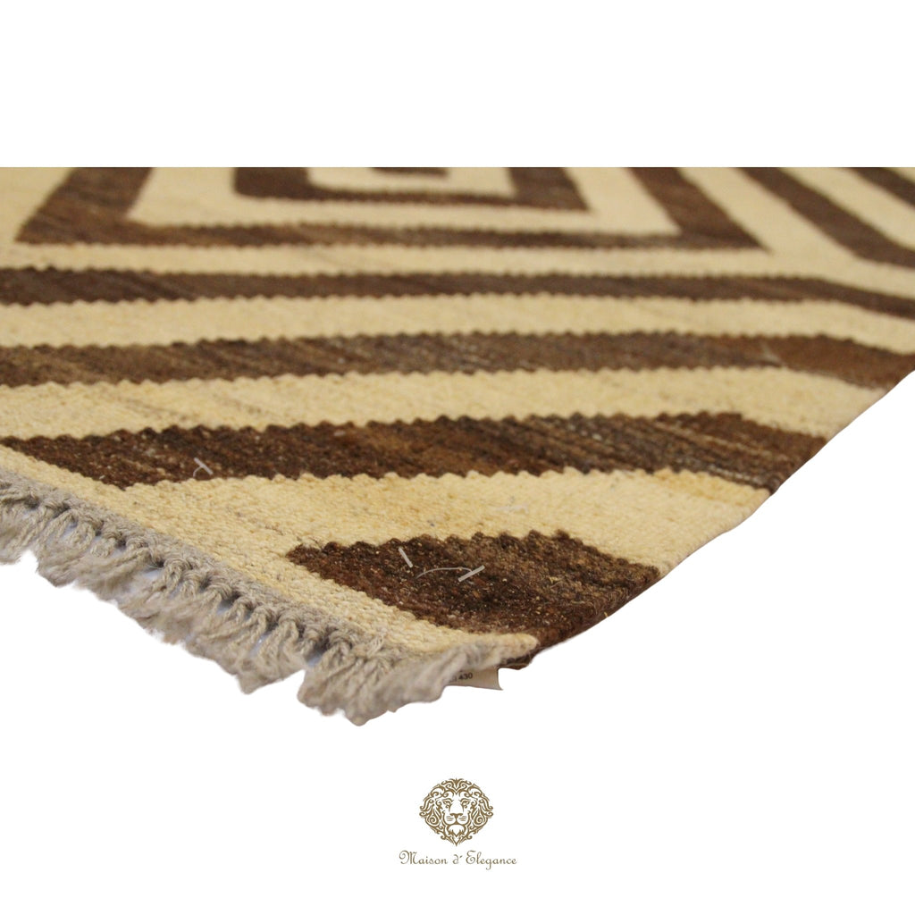 Close-up of a brown and beige patterned rug with fringes on a white background.