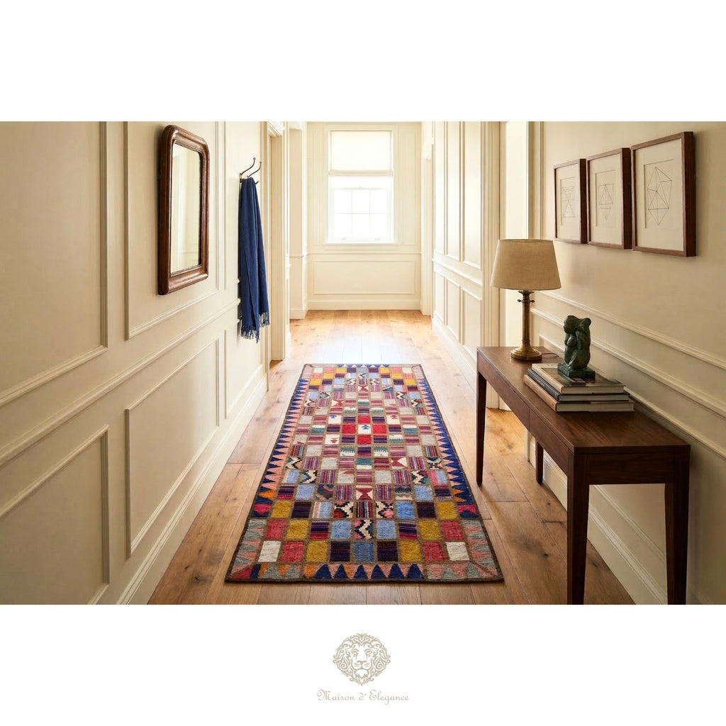 Colorful geometric-patterned rug on a wooden floor in a well-lit hallway with a lamp and books on a table.