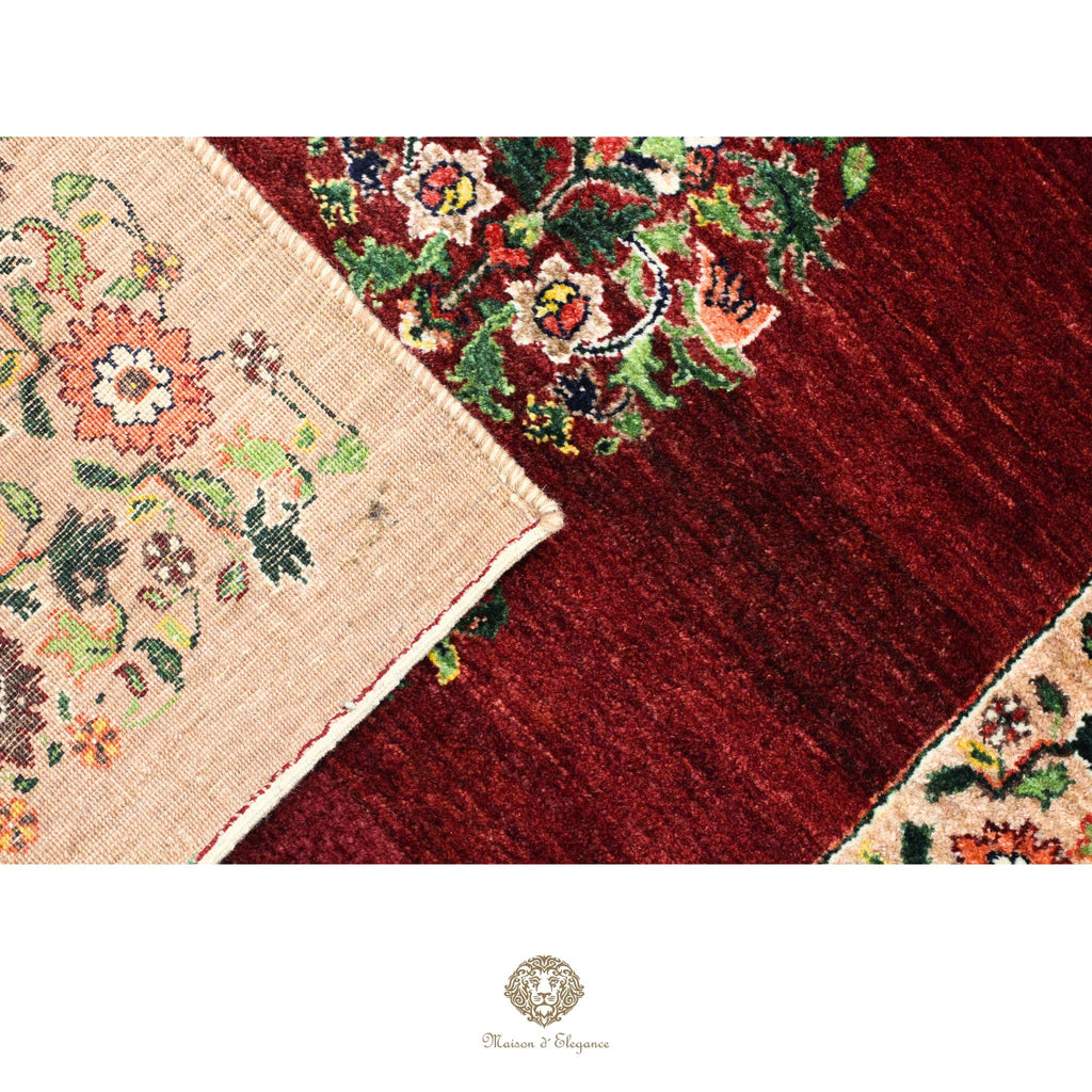 Close-up of a red floral patterned rug with a beige corner showing more intricate designs.