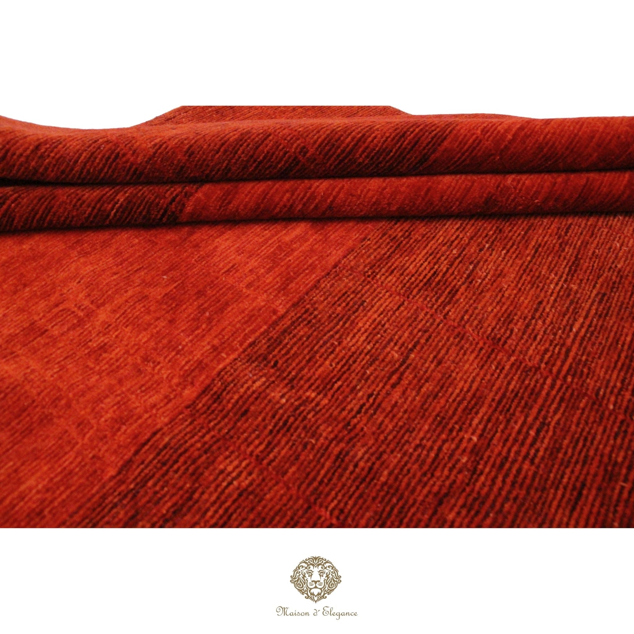 Close-up of red textured fabric with a brand logo at the bottom.