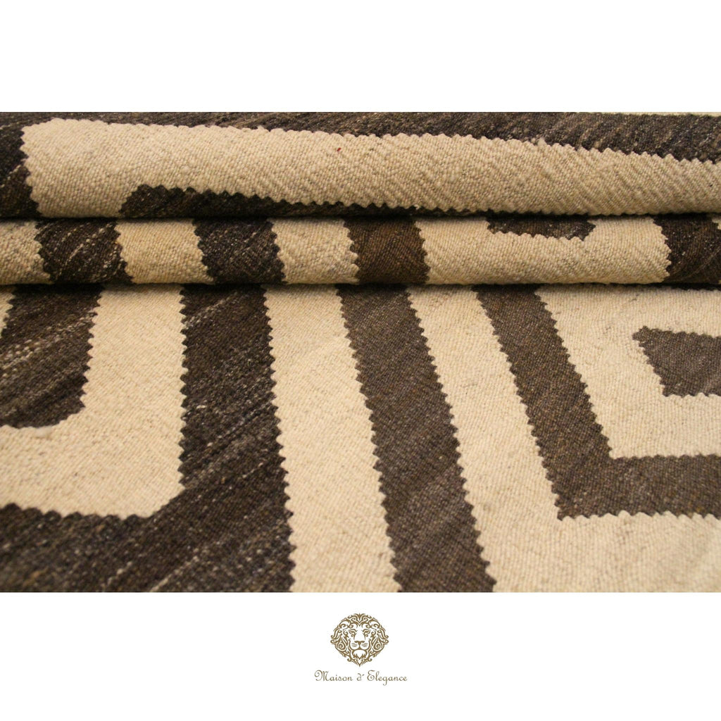 Close-up of a textured fabric with brown and beige pattern, featuring a brand logo at the bottom.