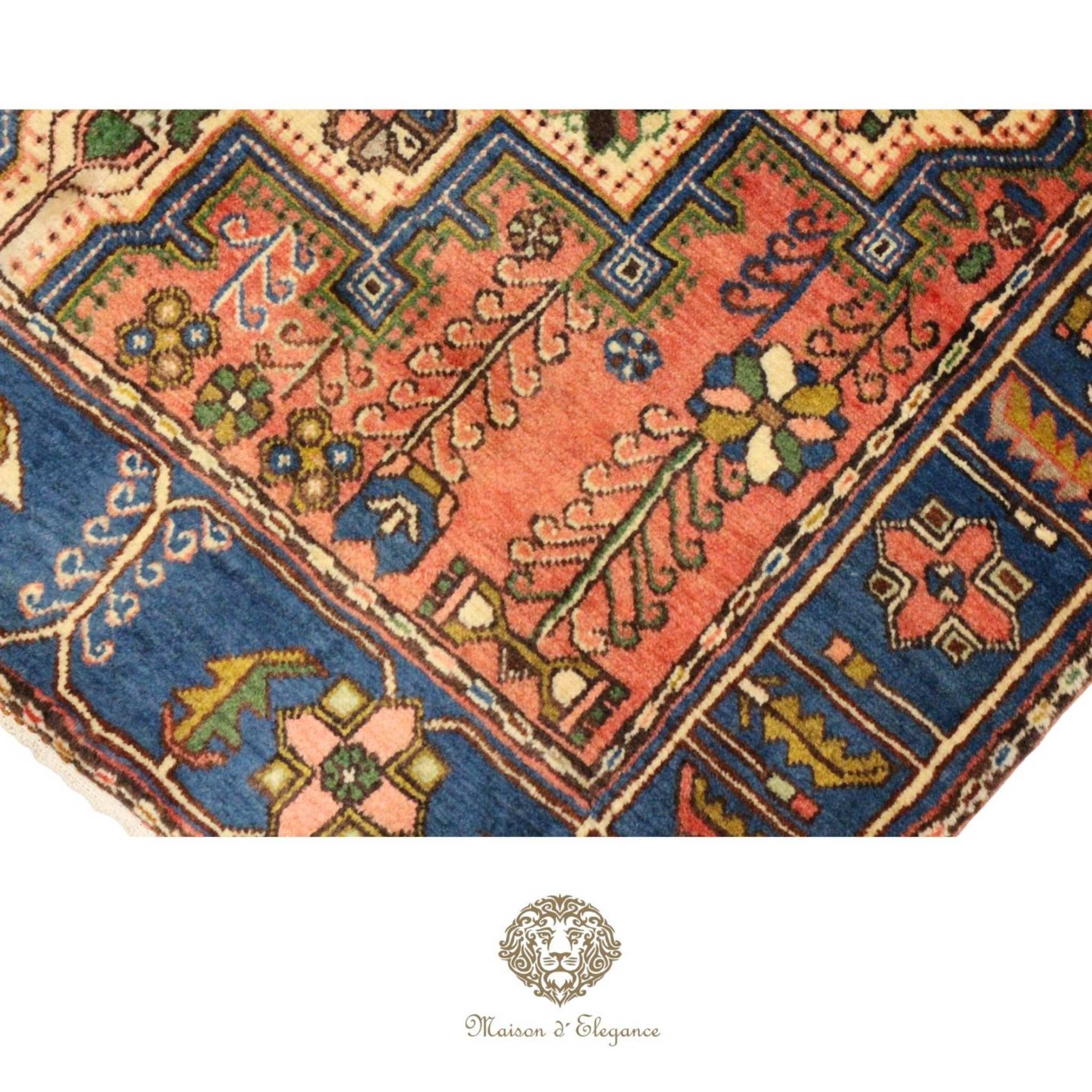 Close-up of a patterned rug with geometric designs, featuring the Maison d'Elegance logo.