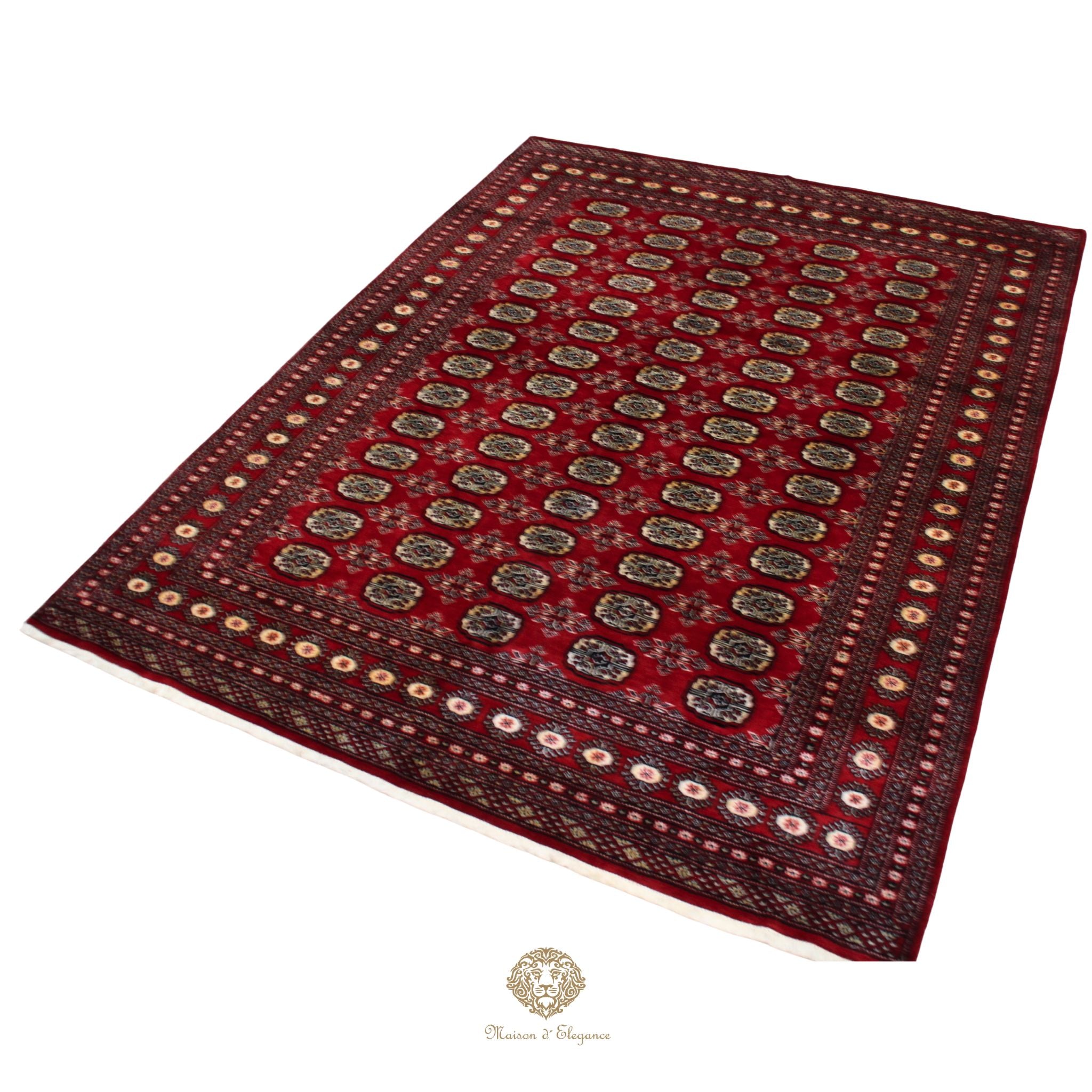Red patterned rug with a brand logo at the bottom center on a white background