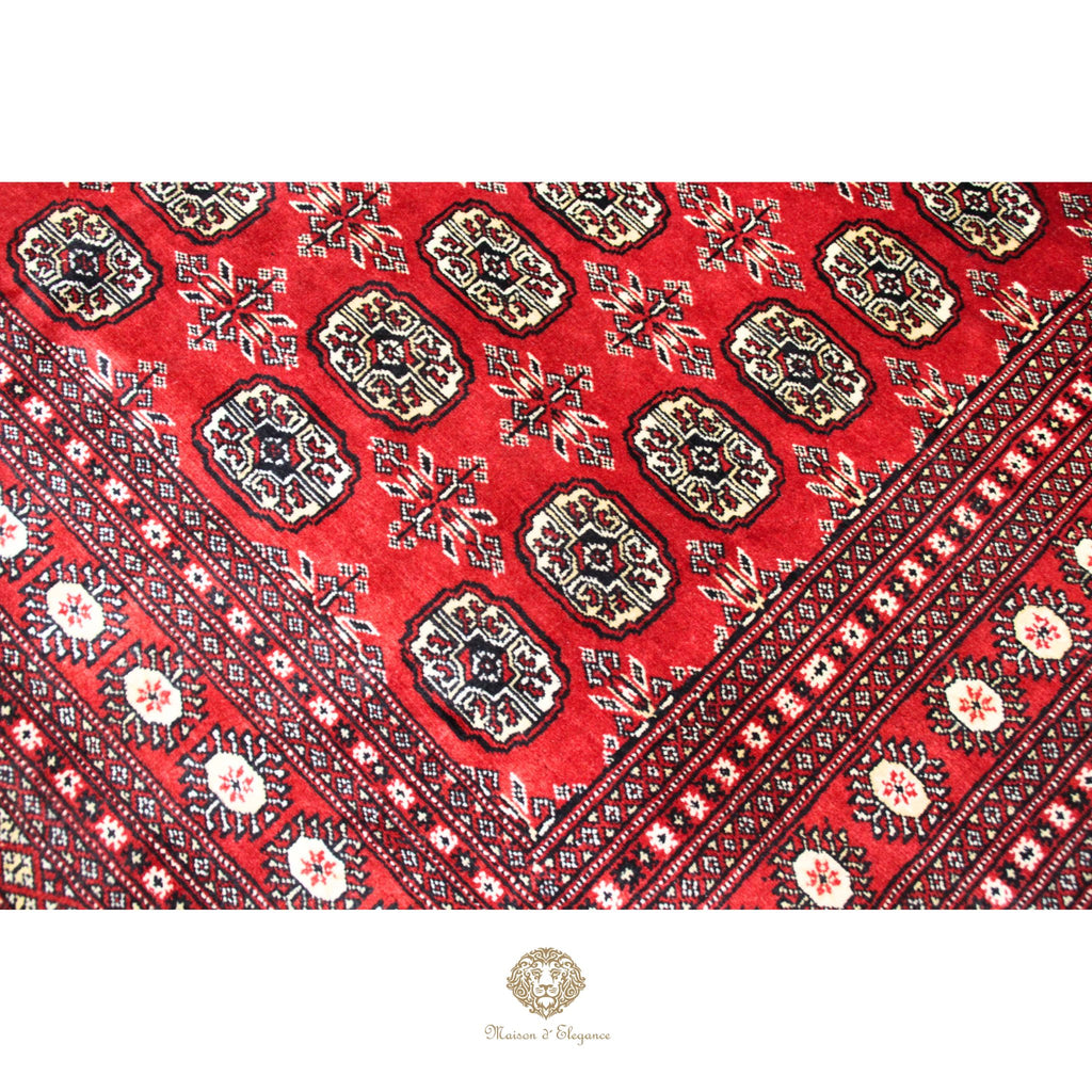 Close-up of a red patterned fabric with intricate designs on a white background.