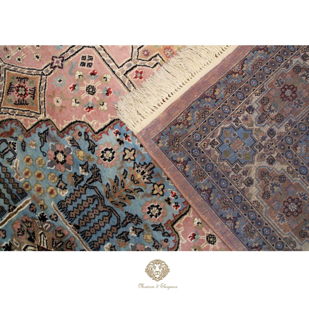 Close-up of a patterned rug with intricate designs on a rosa background.