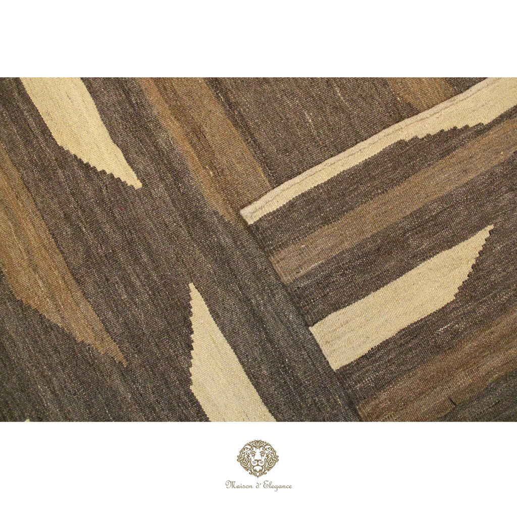 Close-up of a brown and beige patterned rug with a brand logo at the bottom.