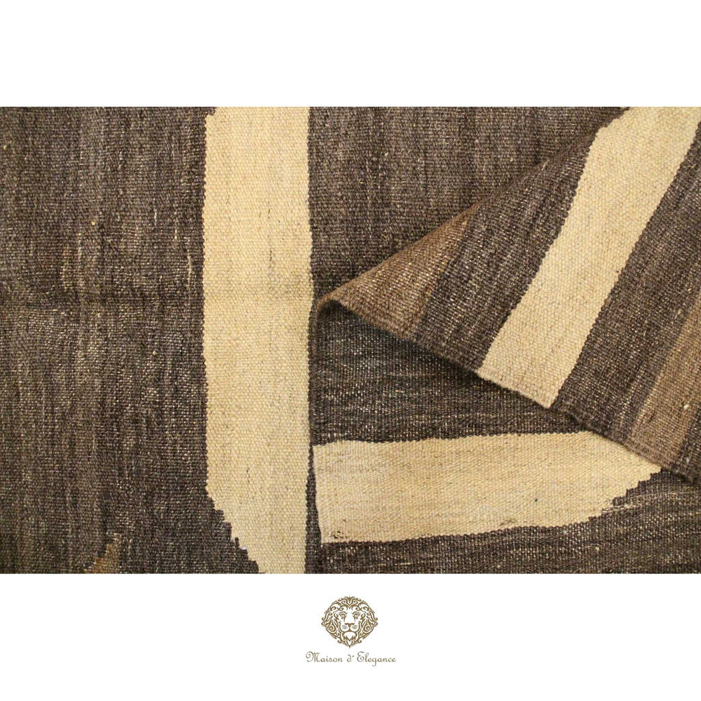 Close-up of a textured brown and beige rug with a brand logo at the bottom.