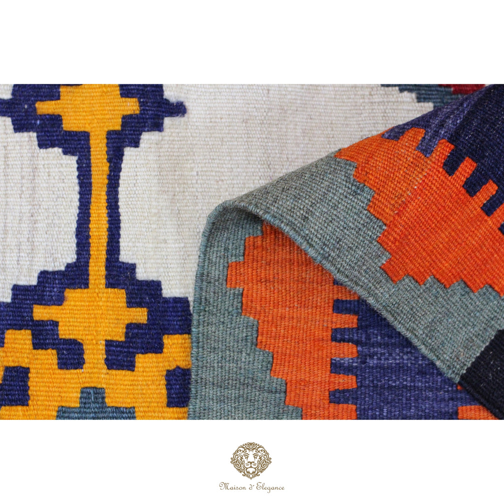 Close-up of a patterned rug with geometric design in blue, orange, and gray.