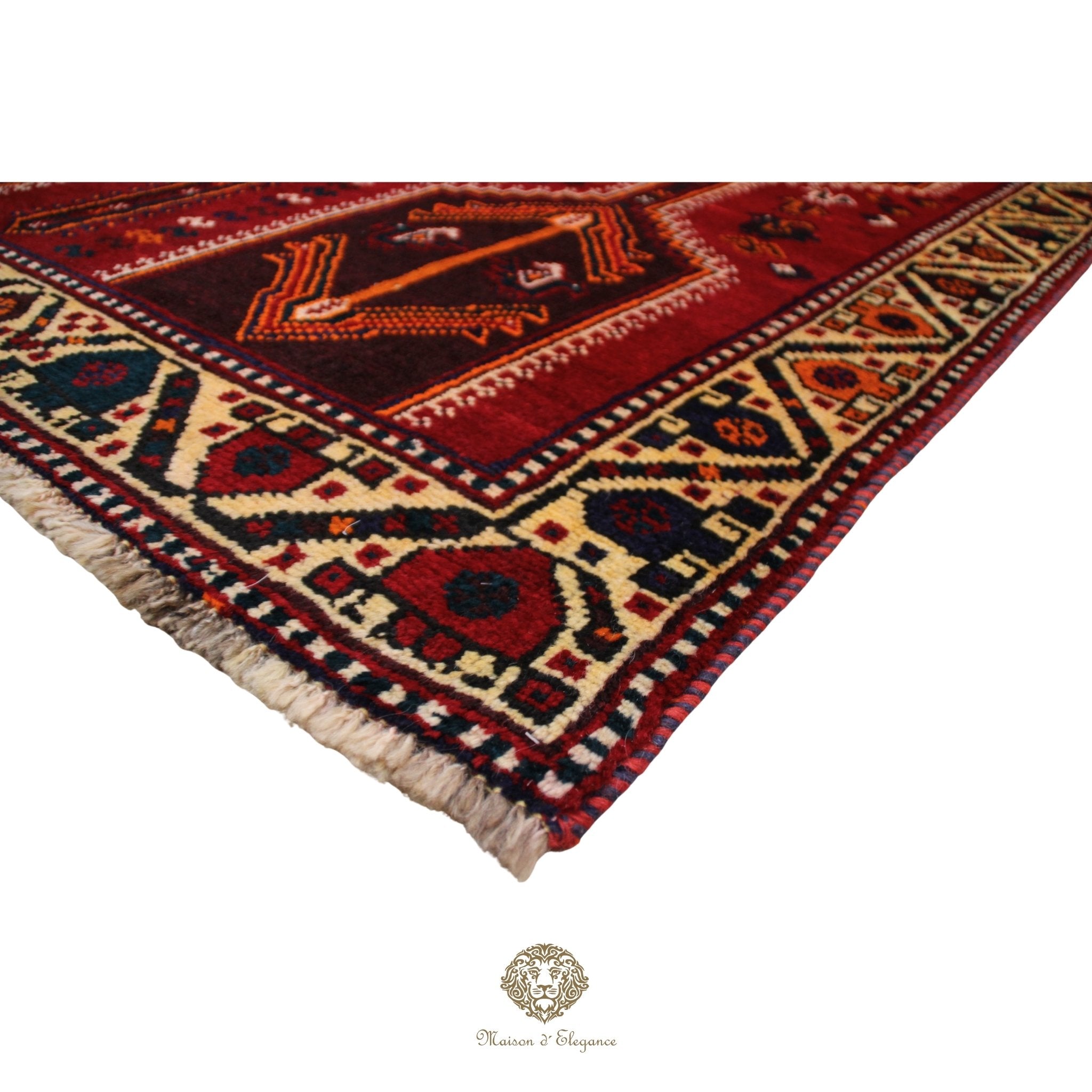 Corner of a patterned rug with intricate designs on a red background